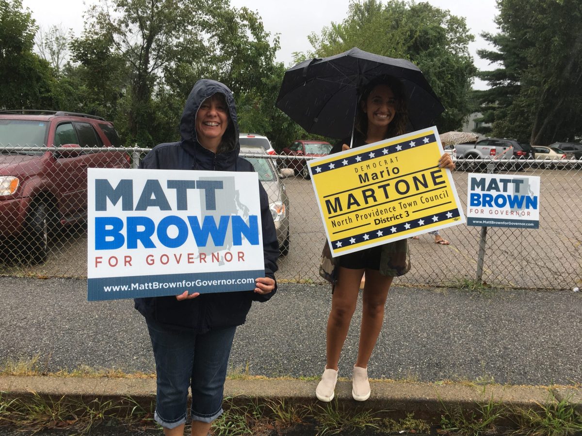 Campaign volunteers stood in front of a polling place with signs, undetered by the wet weather