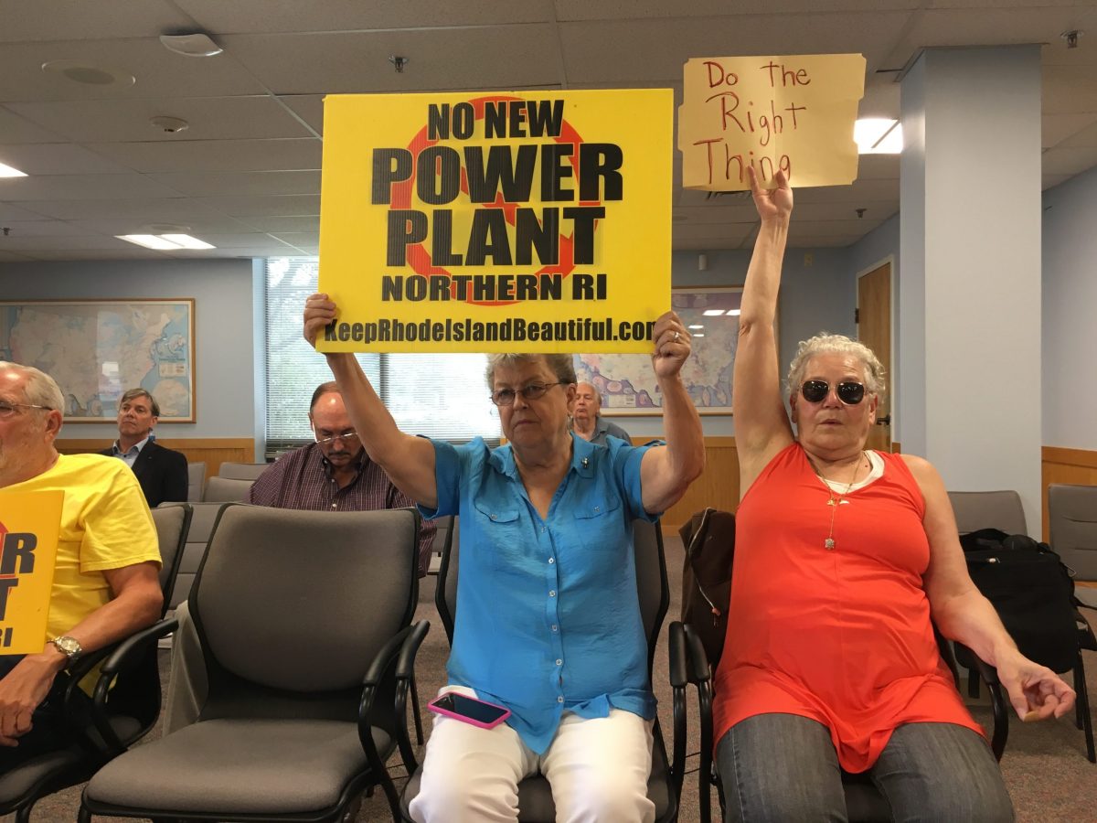 Opponents of the power plant hold signs during a hearing before the Rhode Island Energy Facility Siting Board on Wednesday.