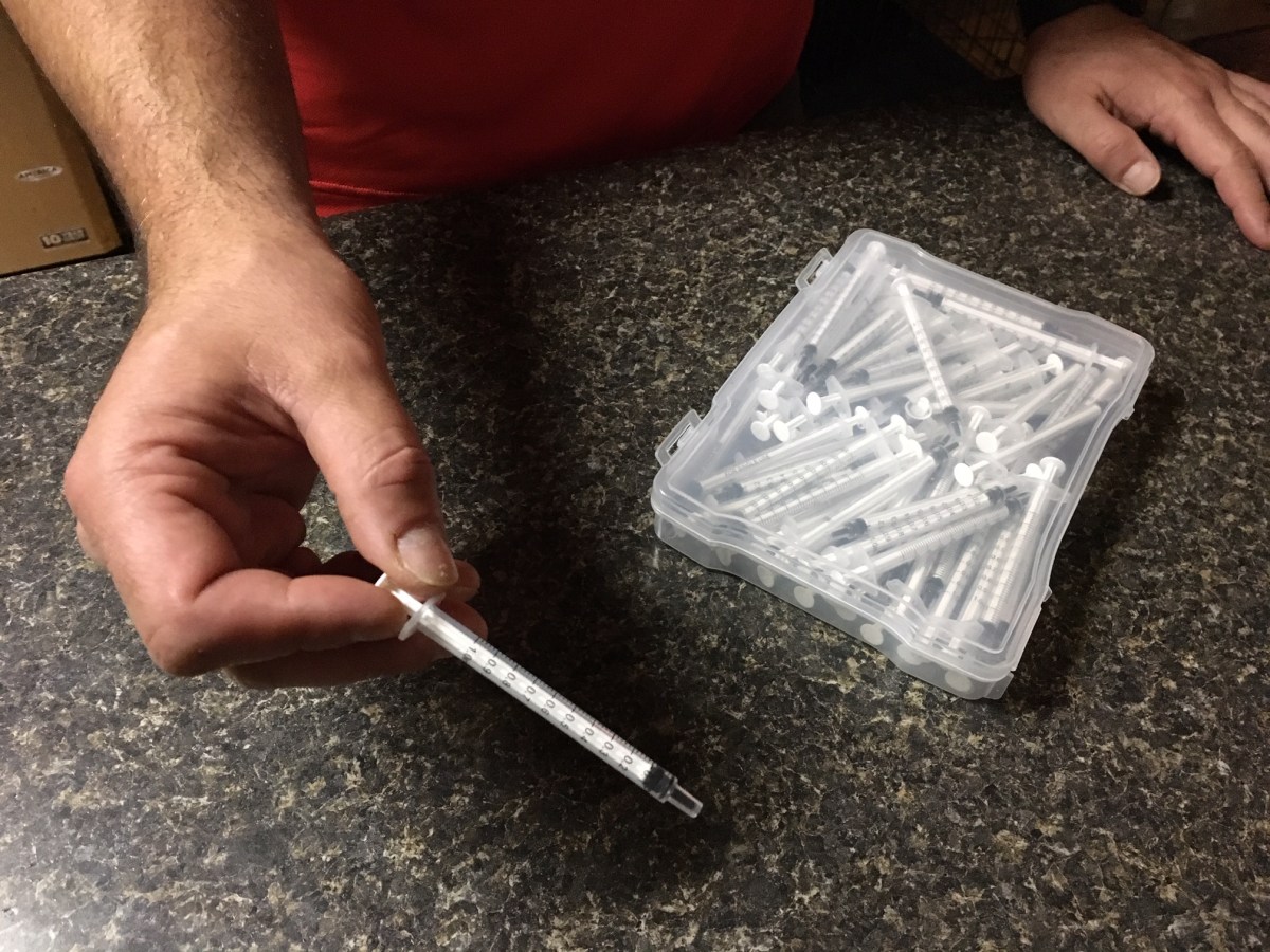 Chris holds plastic dosing syringe for 13-year-old son's medical marijuana oil