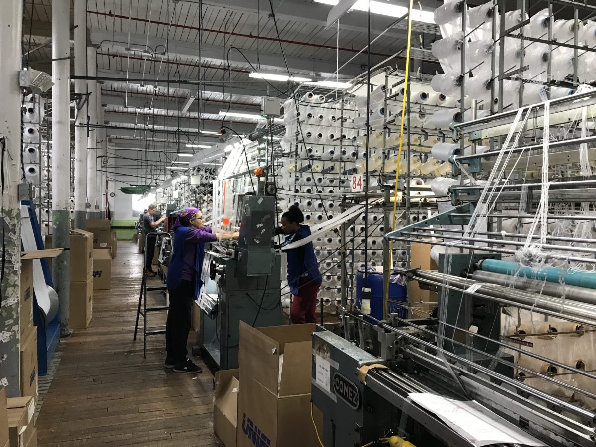 Workers set up a knitting machine.