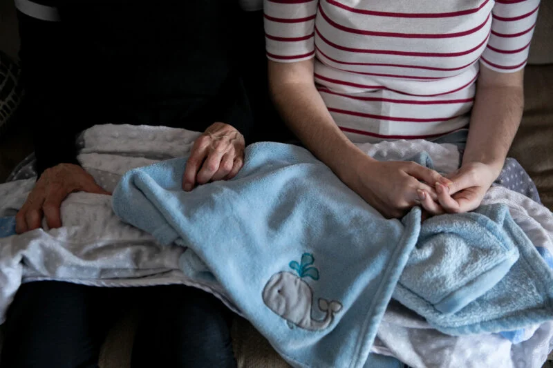 Barbara and Jessica sit with Alijah’s baby blankets at their home.