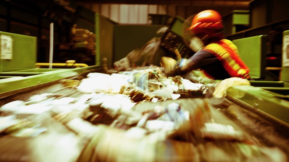 A worker removing contaminants from recycling