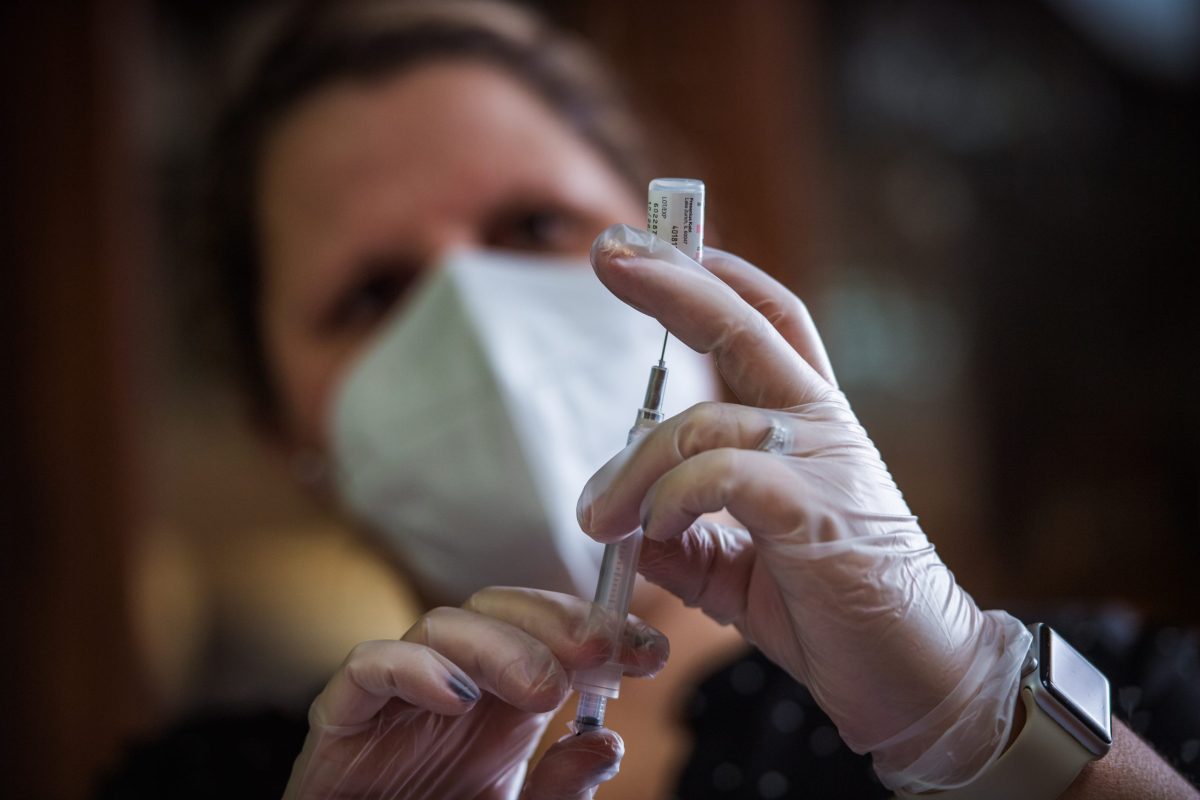 A pharmacist loads a dose of COVID-19 into a syringe at Elmwood Nursing Home in Providence, R.I.