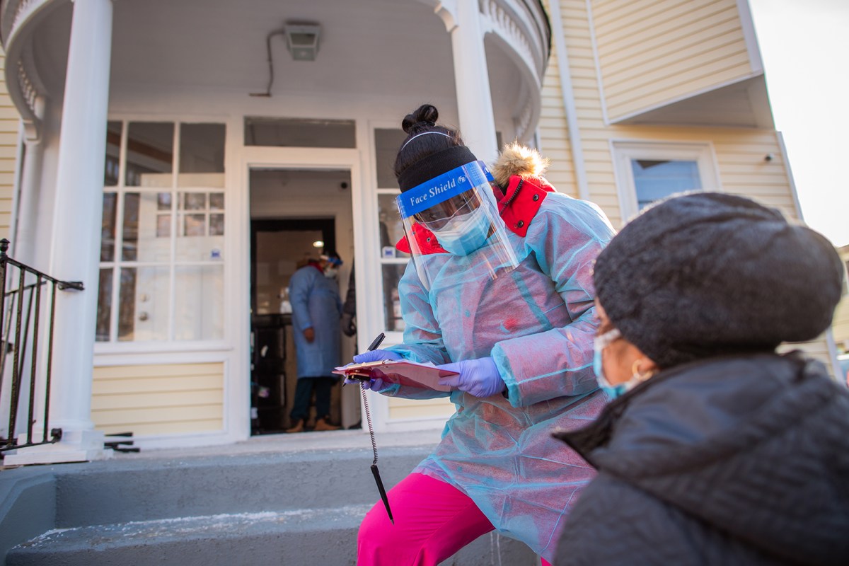 CNA Janete Costa checks information on a patient waiting on line for covid testing conducted by Jenks Park Pediatrics in Central Falls.