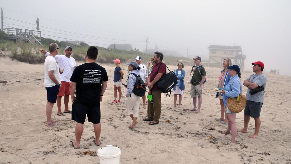 Property owner Keith Wilcox, second from left, speaks with shoreline rights advocates during a seaweed gathering protest, on June 26, 2021.