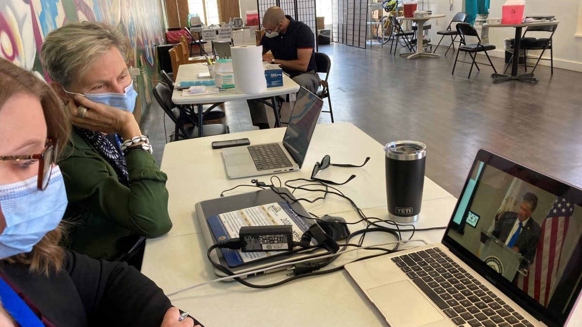 Dr. Annie DeGroot, medical director of Clinica Esperanza, and a colleague watch Gov. Dan Mckee's news conference about their new test-to-treat clinic