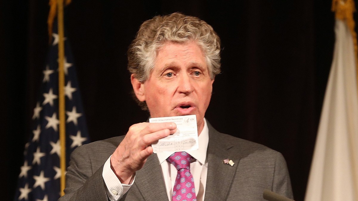 Gov. McKee holds up his COVID-19 vaccine card at an event in April 2021. The governor tested positive for COVID-19 on Saturday evening.