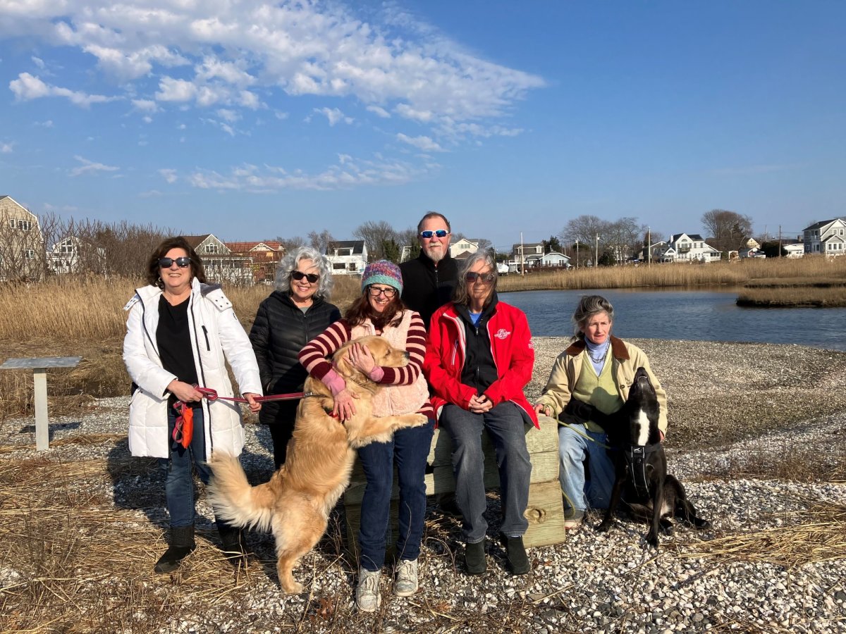 Common Fence Point residents pose in front of Taylor Point saltmarsh in the Portsmouth neighborhood on Tuesday, Feb. 27. 2024. Everyone participates in the CFP Preparedness Committee. The residents planted native grasses and shrubs on the shoreline to prevent erosion and are restoring the saltmarsh to improve the habitat for fish and birds and filter stormwater runoff.