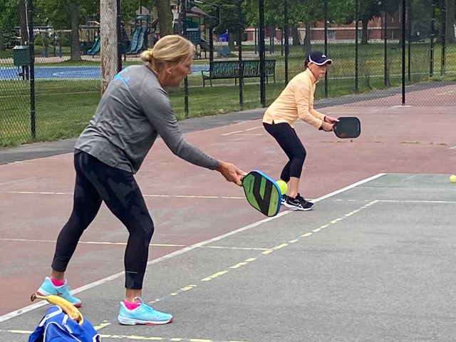 Nancy Tache hits a forehand while partner Michelle Dias stands ready for a return.
