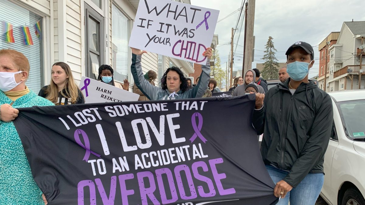 Jennifer Dubois, sign raised, marches to Woonsocket City Hall in April 2022 on the one year anniversary of the death of her 19-year-old son from a drug overdose.