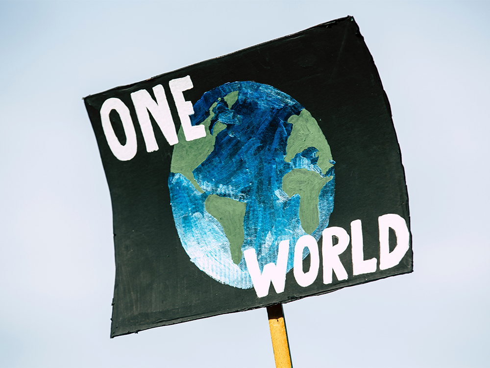 A sign with a painting of the earth, with the text "One World"