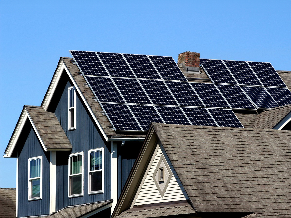 Solar panels the roof of a blue house.