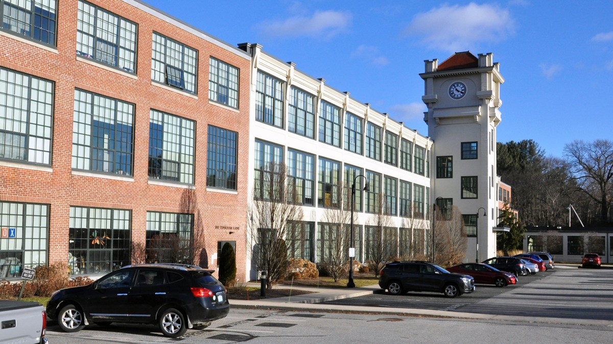 Cars parked in front of a large apartment building with a Clocktower
