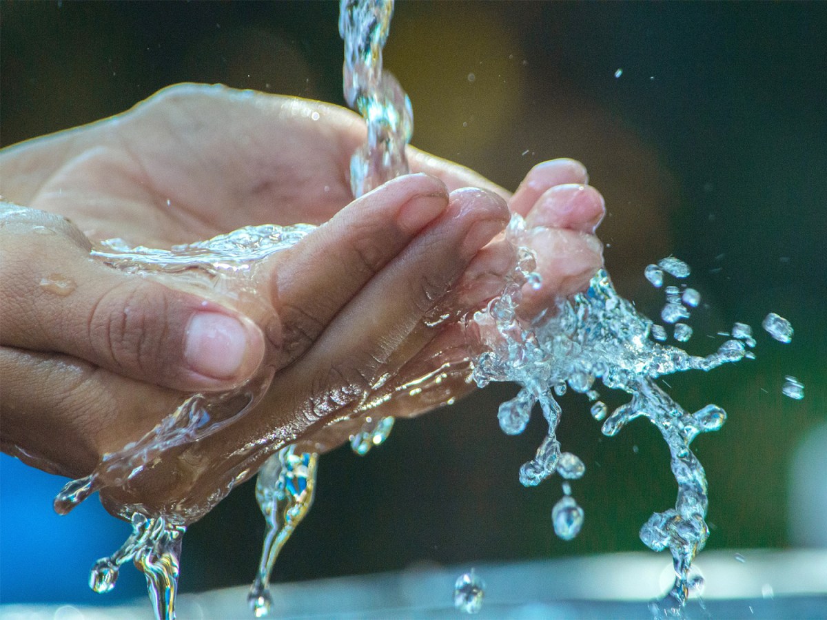 Water coming out of a tap as a person washes their hands