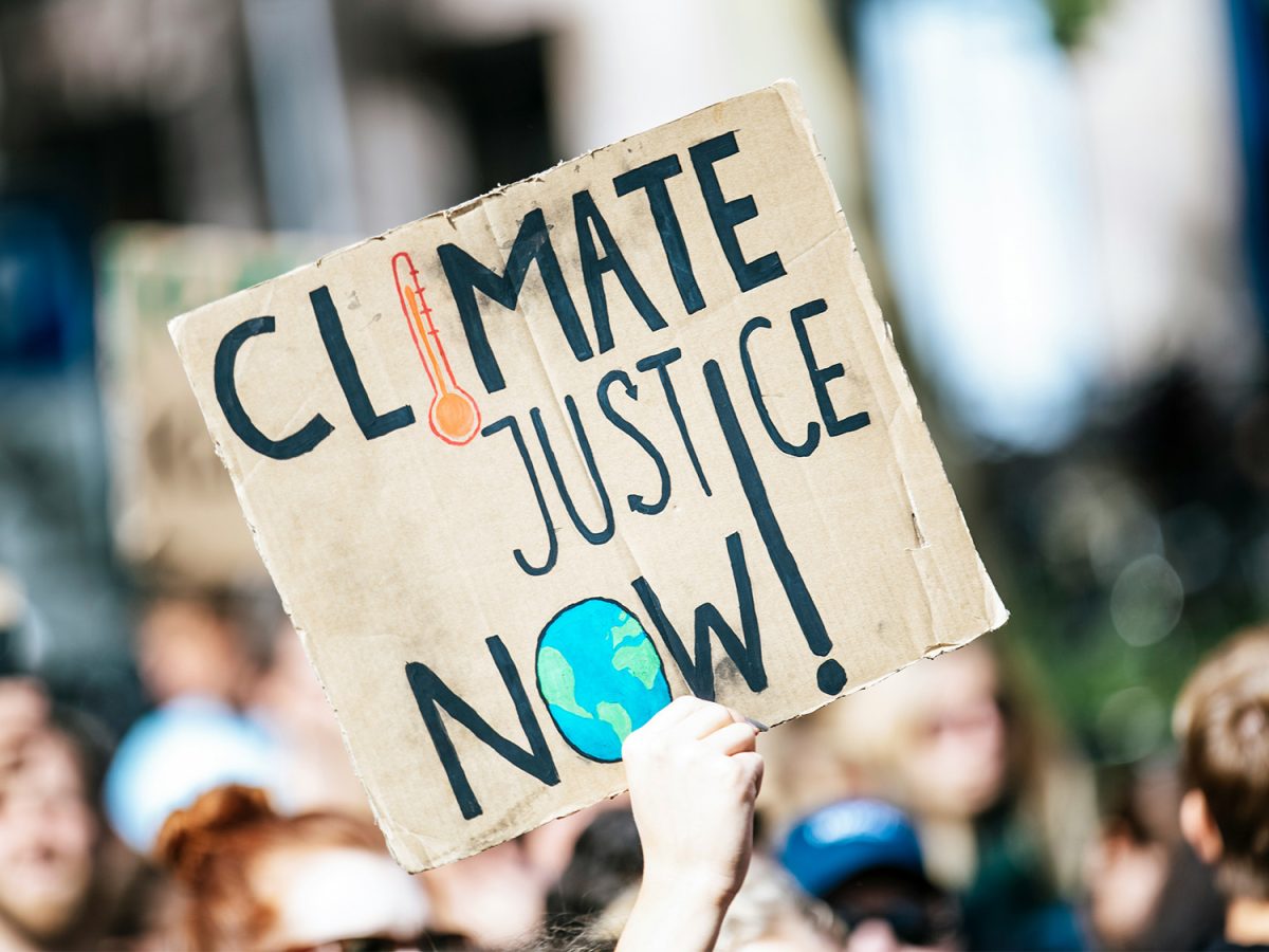 A protestor holds a sign that says "Climate Justice Now!"