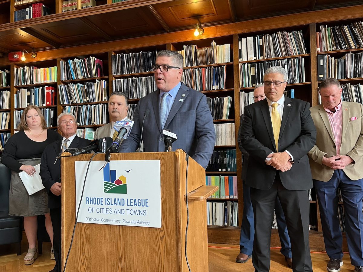 Ernie Almonte, executive director of the Rhode Island League of Cities and Towns, speaks during a Statehouse news conference while surrounded by mayors and town managers