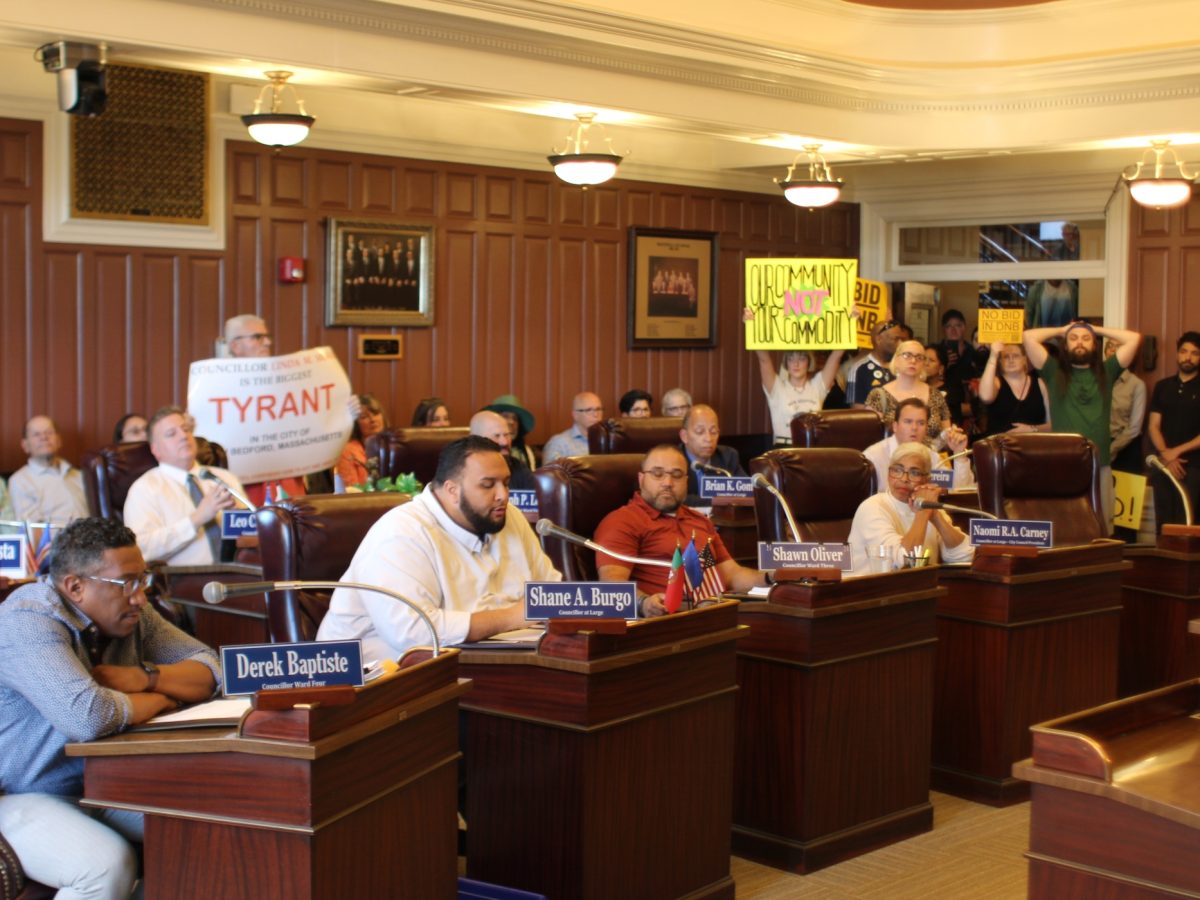 A view inside the New Bedford City Council chamber, with critics of the BID holding signs in the back of the room.