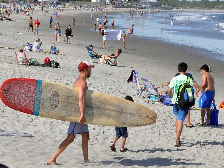 A surfer prepares to enter the water at Narragansett Town Beach.