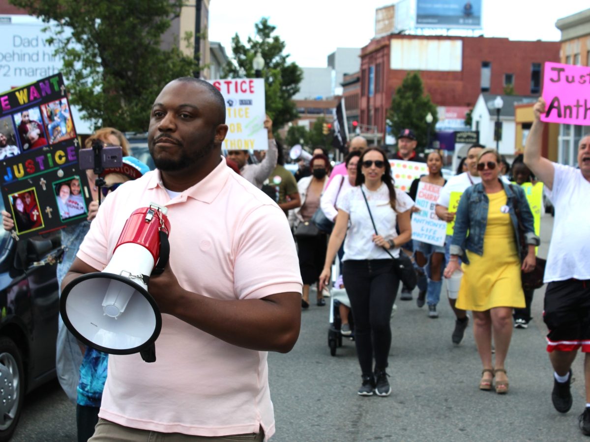 Anthony Harden's brother, Carl Harden, leads a crowd of protesters down South Main Street in Fall River.